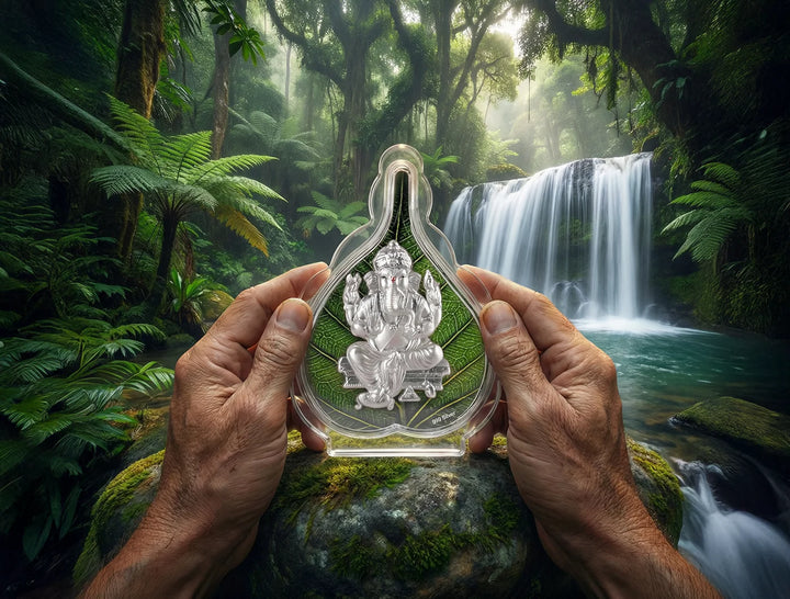 999 Silver Pure Ganesh Green Pan Stand held in hands amidst lush greenery and waterfall background.