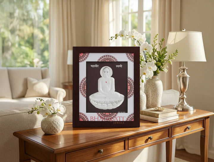 999 Pure Silver Mahavir Swami in a decorative hanging frame on a stylish table in a bright living room.